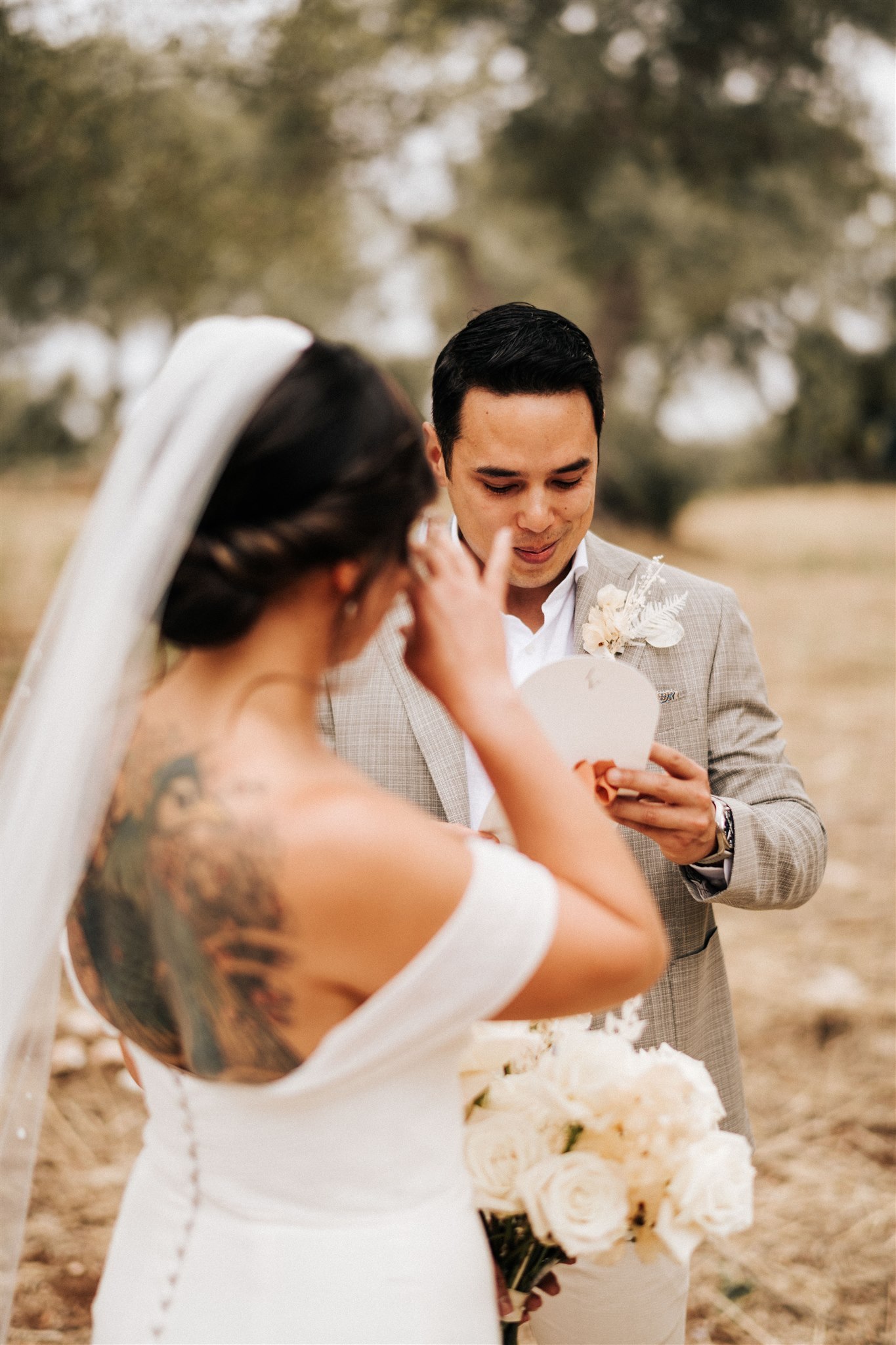 Bride and groom eloping in an olive grove in Ostuni, Puglia. The bride is crying while the groom is reading the vows