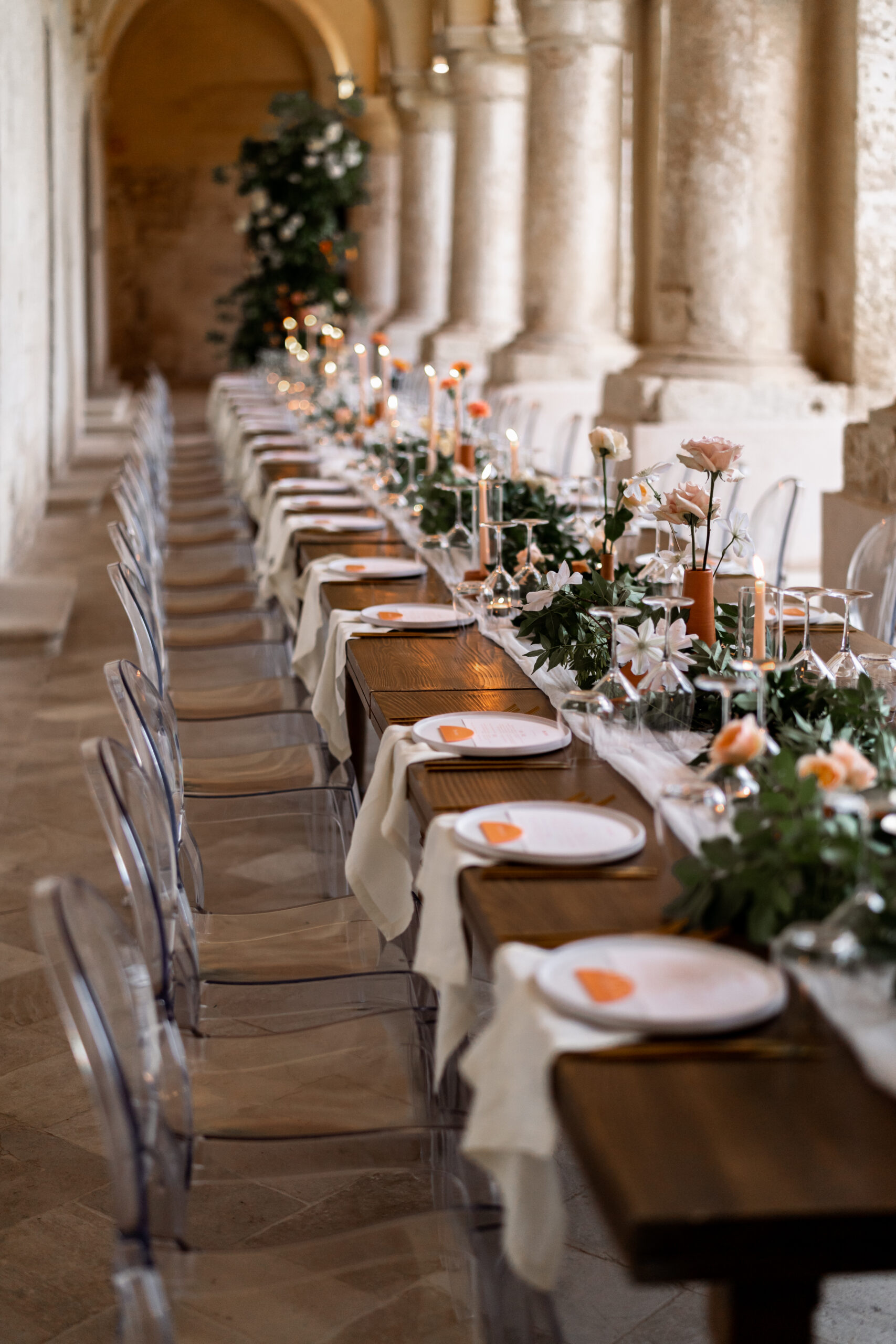 Wedding table with curated terracotta details and bespoke plates set under the columns of a period venue in Puglia, Italy